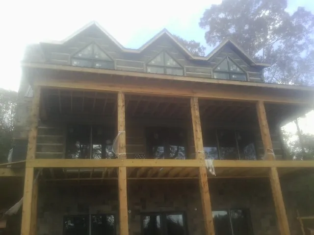Dormers and porch framing on a large log home under construction — Roof Coating work by our crew in Littleton