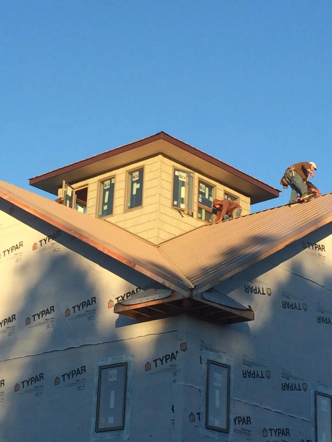 Roofers working around a rooftop cupola on a new metal roof at sunset — Roof Waterproofing in Littleton by Roofing Brothers